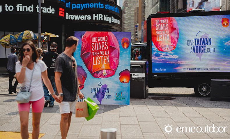 An image of people walking on the sidewalk looking at outdoor advertising.