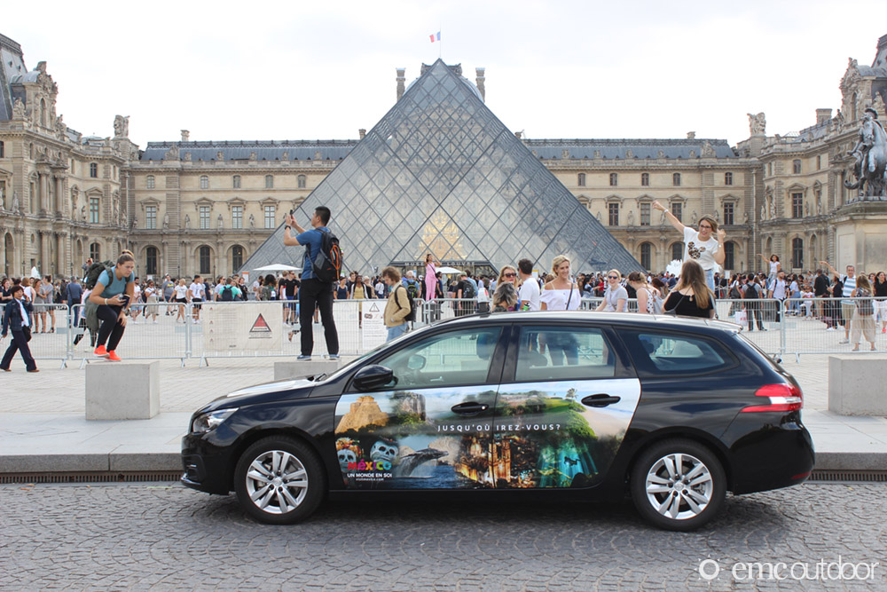 a wrapped car advertising mexico tourism parked in front of the Louvre