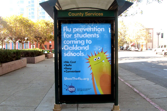 a transit shelter showing a message for flu vaccines