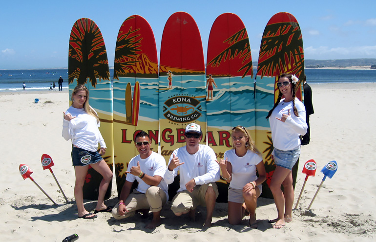 Image of a street team on the beach with a wall of branded surfboards